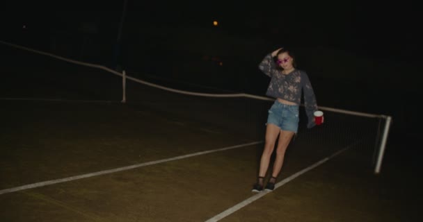 Hipster dronken tiener meisje wandelen en morsen drankjes feesten buiten — Stockvideo