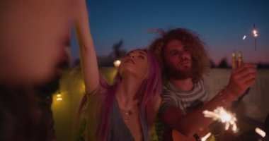Hipster çift çatıdaki yaz partisinde maytaplara bayılıyor.