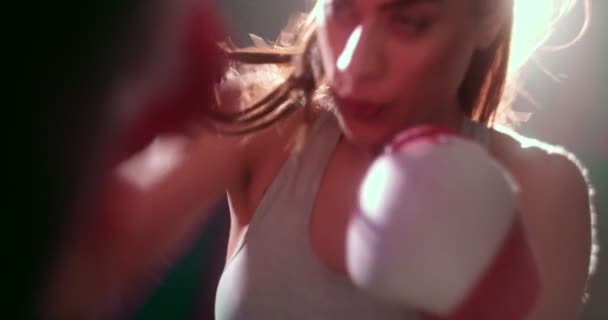 Молодая женщина боксер упорно тренируется с боксерской сумкой — стоковое видео
