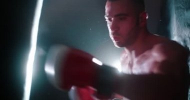 Erkek kickboks sporcusu kum torbasında yumruklarını çalışıyor.