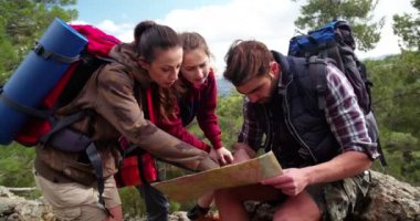 Yürüyüş arkadaşları dağlarda bir harita üzerinde çalışıyorlar. Yerlerini tespit ediyorlar.