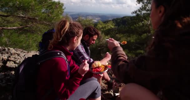 Amigos excursionistas comiendo en la cima de una montaña — Vídeos de Stock