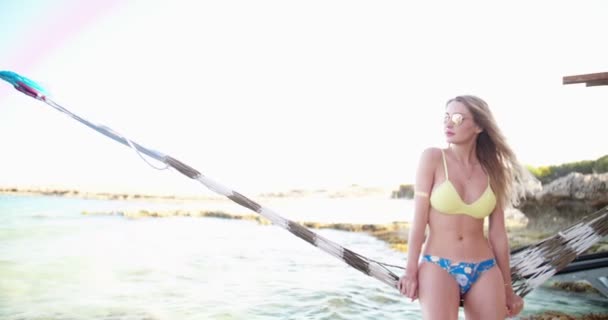 Woman in bikini relaxing on a hammock at the beach — Stock Video