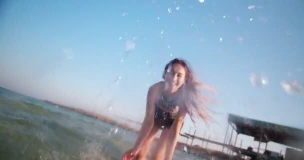 Hermosa joven que se divierte salpicando agua en el mar — Vídeo de stock