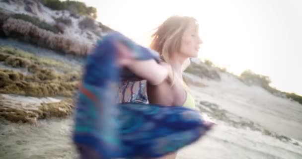Mooie vrouw in bikini met zomersjaal aan het strand — Stockvideo