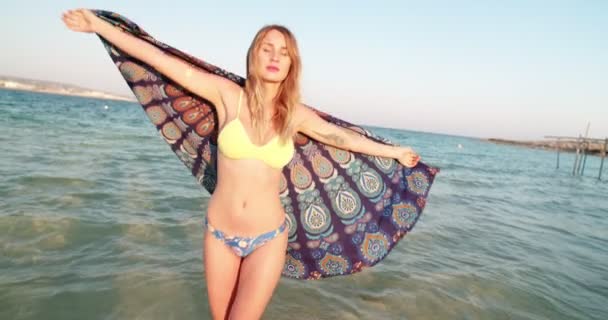 Young woman in swimwear holding a scarf at the beach — Stock Video