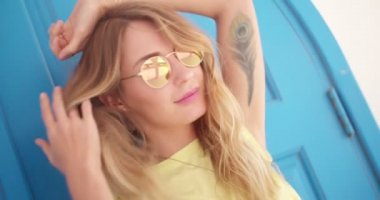 Akdeniz adasındaki kadın eski mavi kapının önünde duruyor.