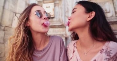 Genç hippi kadınlar eski kasabada pembe sakız üflüyorlar.