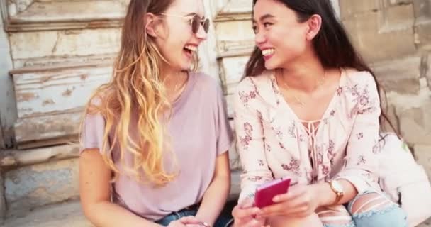 Молодые женщины смотрят на фотографии на смартфоне и смеются — стоковое видео
