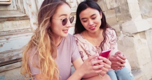 Молодые женщины проверяют социальные сети на смартфоне и смеются — стоковое видео