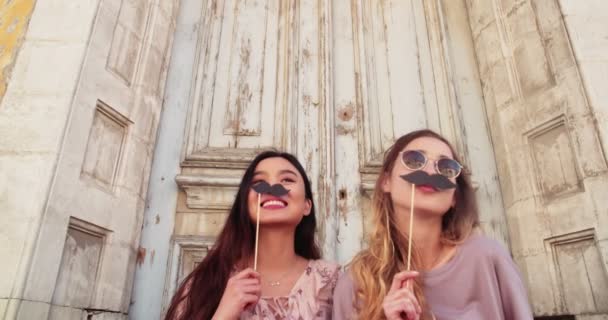 Jovens hipster mulheres se divertindo com bigodes falsos em paus — Vídeo de Stock