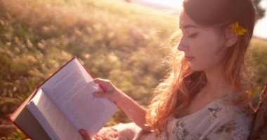 Kırsalda bir çayırda kitap okuyan bir kız.