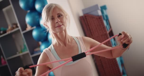 Active senior woman stretching her arms with resistance band — Stock Video