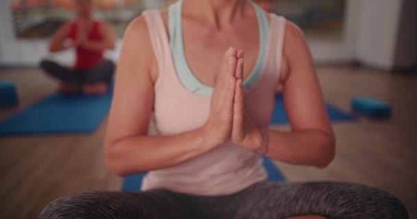 Senior woman mediating in yoga class in the lotus position — Stock video