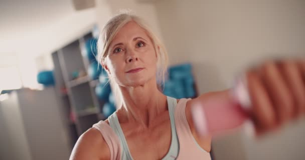 Krásná starší žena pracuje s činkami v tělocvičně — Stock video