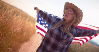 Kırsal bölgede bayrak taşıyan Amerikalı kadın.