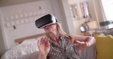 Kıdemli kadın evde sanal gerçeklik simülatörüyle eğleniyor.