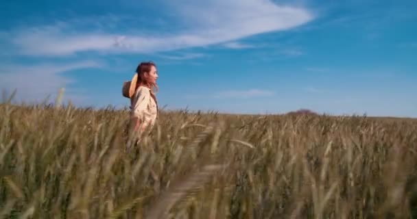 Beautiful female farmer holding wheat plants walking in field — Stock Video