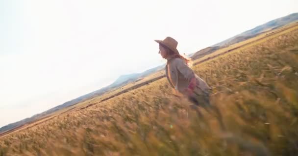 Vacker ung kvinnlig bonde som springer bland grödor med utsträckta armar — Stockvideo