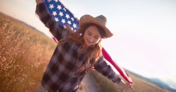 美丽的年轻女子拿着美国国旗在金碧辉煌的田野中奔跑 — 图库视频影像