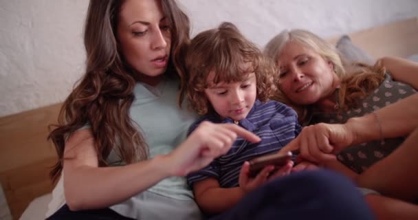 Grootmoeder, dochter en kleinzoon spelen samen aan de telefoon — Stockvideo