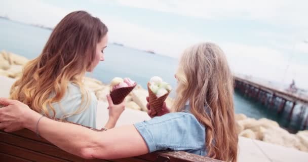 Beautiful grandmother and granddaughter eating ice cream by the sea — Stock Video