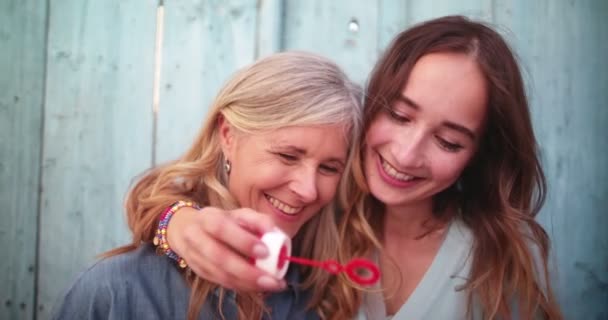 Χαριτωμένη ώριμη μητέρα και η νεαρή κόρη φυσάει φυσαλίδες μαζί σε εξωτερικούς χώρους — Αρχείο Βίντεο