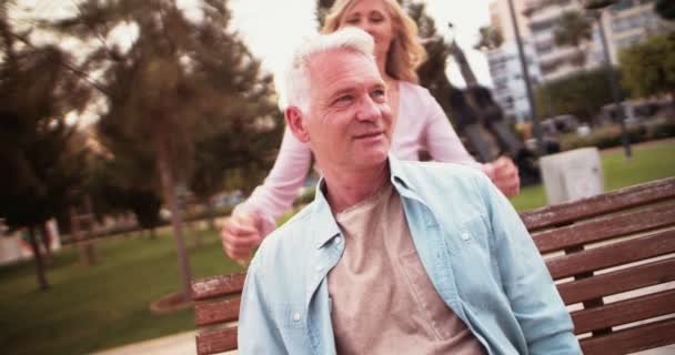 Senior fru överraskande make med kram och kyss i parken — Stockvideo