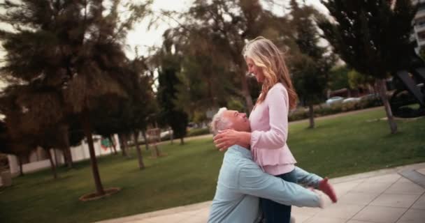 Cheerful senior man lifting his wife up in park — Stock Video