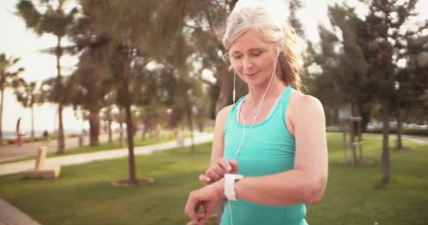 Sportliche Seniorin verfolgt ihre Laufleistung auf Smartwatch — Stockvideo