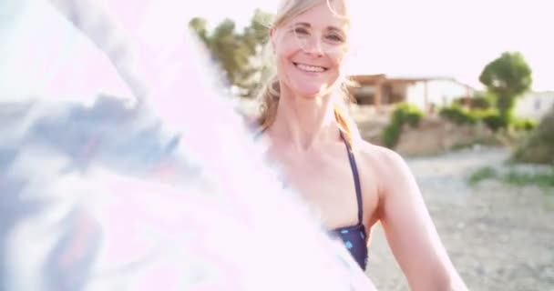 Happy senior woman with scarf on the beach at sunset — Stock Video