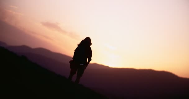 Mujer excursionista con los brazos extendidos en el borde de la montaña al atardecer — Vídeos de Stock