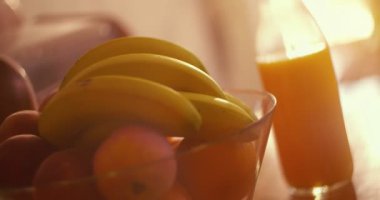 Sabah ışığında meyve kasesi ve portakal suyu şişesi.