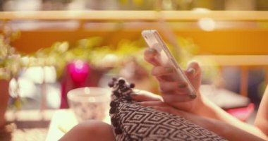 Genç, rahat bir kadın dışarıda oturuyor ve akıllı telefondan mesaj atıyor.