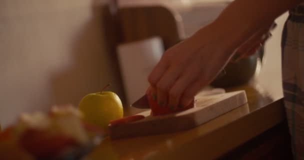 Молодая женщина режет яблоко ножом на доске — стоковое видео