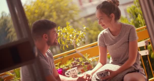 Νεαρό ζευγάρι hipster χαλαρώνοντας στο μπαλκόνι διαμέρισμα το πρωί — Αρχείο Βίντεο
