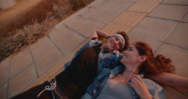 Romántica pareja de adolescentes hipsters coqueteando acostados en el pavimento — Vídeos de Stock