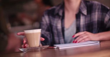 Çizim defteri olan genç bir kadın sanatçı kafede kahve içiyor.