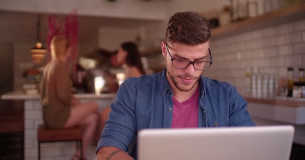 Junger Hipster-Mann forscht in modernem Café am Laptop — Stockvideo
