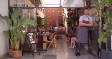 Genç hippi kafe müdürü dükkan girişinde duruyor.