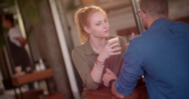 Genç hippi çift kahve içiyor ve şehir kafesinde konuşuyor.