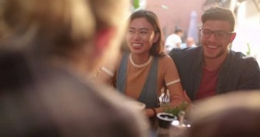 Genç, çok ırklı hippi çift, kafede arkadaşlarıyla eğleniyor.