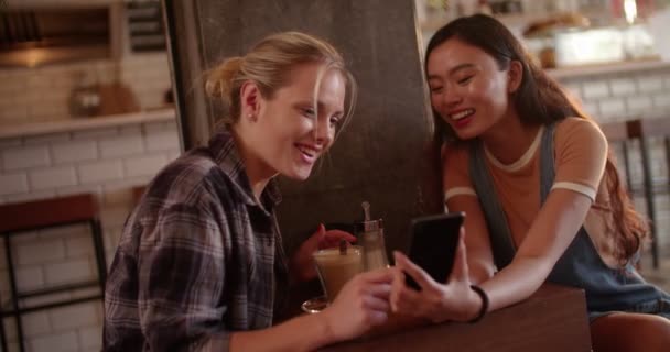 Jóvenes mujeres hipster con teléfono inteligente divertirse en la cafetería urbana — Vídeos de Stock