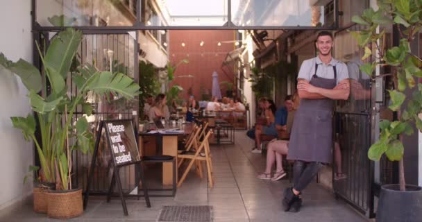 Jonge hipster cafe manager staat bij winkelingang — Stockvideo
