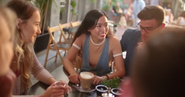 Νεαρό πολυεθνικό hipster ζευγάρι χαλαρώνοντας και πίνοντας καφέ με τους φίλους — Αρχείο Βίντεο