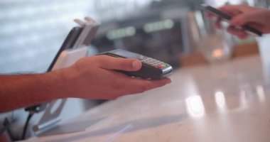 Akıllı telefonu olan bir kadın restoranda temas teknolojisini kullanarak ödeme yapıyor.