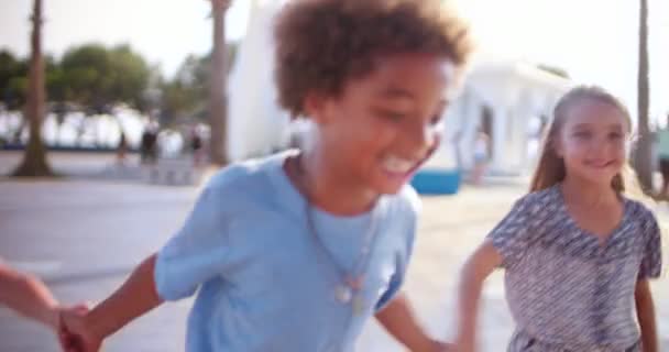 Πολυεθνικά υιοθετημένα παιδιά της οικογένειας στις καλοκαιρινές διακοπές τρέχουν κρατώντας τα χέρια — Αρχείο Βίντεο