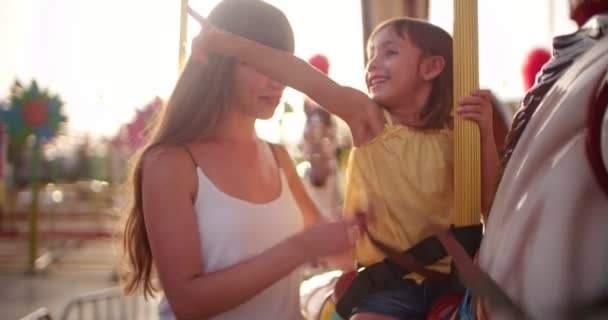 Mother and daughter having fun on carousel ride at funfair — Stock Video