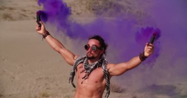 Çöl müzik festivalinde sis bombalarıyla kutlama yapan genç adam.
