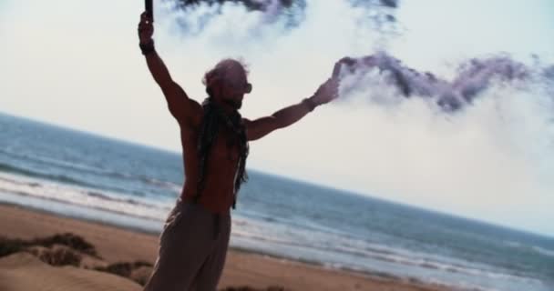 Junger Mann hält Rauchbomben am Strand — Stockvideo